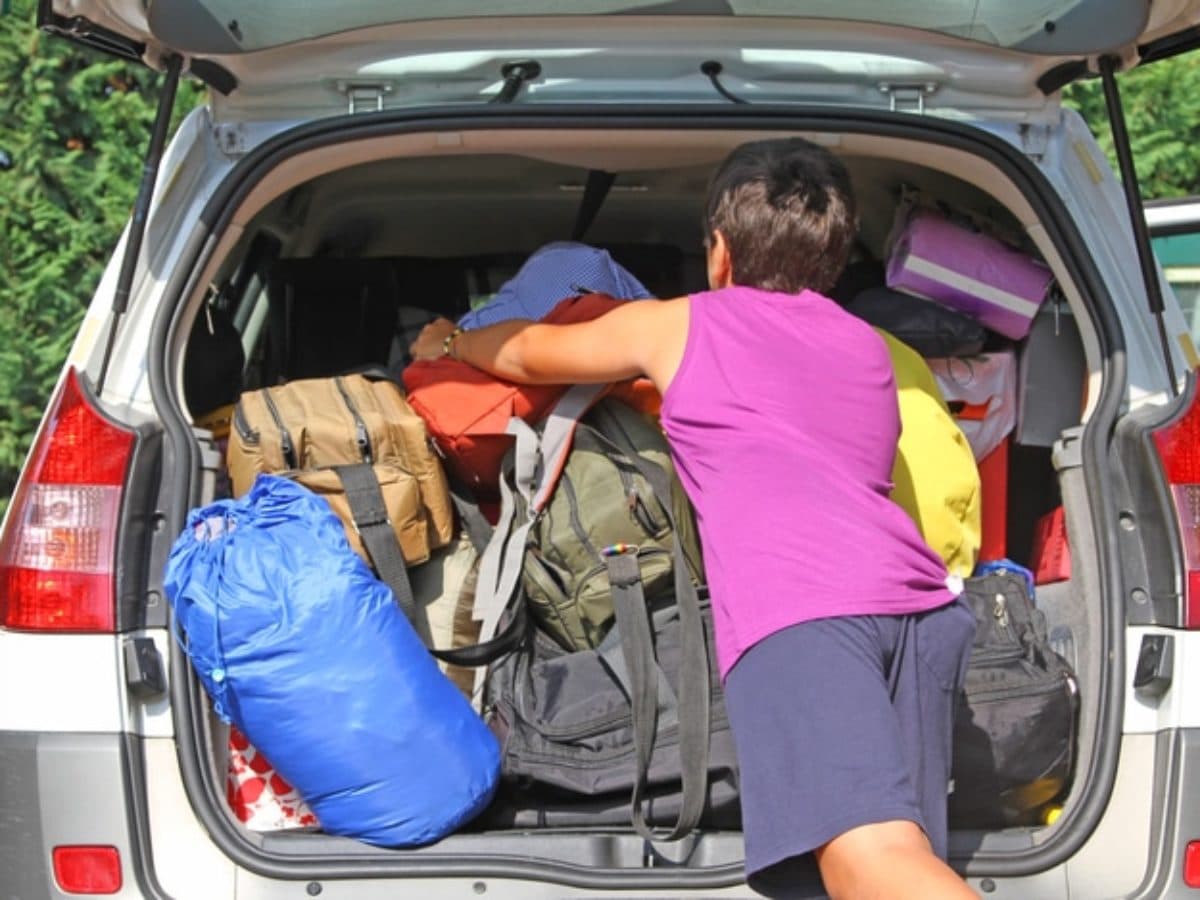 En tant qu'expert en code de la route belge, voici une description détaillée de l'image pour comprendre le contexte de la question :
Contexte de la question: "Je me prépare à effectuer un long voyage et j'ai fort chargé mon véhicule :"
Description détaillée de la situation :
Type de situation routière :
La situation présentée n'est pas une scène routière dynamique (intersection, route en circulation) mais une scène statique de préparation de véhicule. Il s'agit d'un véhicule de tourisme à l'arrêt, probablement stationné dans une allée privée, un parking, ou devant un domicile, en train d'être chargé. L'arrière-plan montre de la végétation dense (arbres ou buissons), suggérant un environnement extérieur et non urbain directement sur une chaussée.
Éléments visibles :
Véhicule : L'arrière d'une voiture de tourisme (probablement un break ou un monospace) de couleur claire (gris clair ou blanc cassé) est visible. Le hayon du coffre est grand ouvert, révélant l'intérieur du compartiment de chargement. Les feux arrière du véhicule sont visibles (optiques rouges et orange/blanches), mais sont éteints, la voiture étant à l'arrêt.
Personne : Une personne, vue de dos, portant un débardeur violet et un short foncé, est penchée dans le coffre, les bras étendus, semblant organiser, pousser ou tenter de faire rentrer davantage de bagages.
Contenu du coffre : Le coffre est extrêmement rempli. On y voit une multitude de sacs, sacs à dos, sacs de voyage et autres articles de tailles et couleurs variées (bleu, marron, orange, jaune, noir, violet). Le chargement dépasse visiblement le niveau du seuil du coffre et s'empile très haut, semblant occuper tout l'espace disponible, y compris potentiellement la visibilité par la lunette arrière si elle était fermée.
Autres éléments : Aucune signalisation routière (panneaux, feux de signalisation) n'est présente. Aucun marquage au sol n'est visible. Le temps semble clair et ensoleillé.
Position et direction des véhicules :
Un seul véhicule est visible. Il est à l'arrêt, le coffre grand ouvert, sa partie arrière faisant face au spectateur. Sa direction de déplacement n'est pas pertinente dans cette scène de préparation, mais il est positionné pour être chargé.
Panneaux de signalisation présents et leur signification :
Il n'y a aucun panneau de signalisation visible sur cette image.
Tout autre élément pertinent pour comprendre la situation :
La clé de la situation réside dans le chargement excessif et potentiellement mal arrimé du véhicule. Cette image illustre la problématique soulevée par la question d'examen : "j'ai fort chargé mon véhicule".
Le volume de bagages est tel qu'il compromet probablement la visibilité du conducteur vers l'arrière (lunette arrière obstruée).
Le chargement semble empilé sans un arrimage adéquat, ce qui présente un risque de déplacement des objets en cas de freinage brusque ou de virage, mettant en danger les occupants du véhicule.
Un tel chargement peut également avoir des conséquences sur la stabilité et le comportement routier du véhicule (centre de gravité modifié, distances de freinage allongées, tenue de route altérée), et potentiellement dépasser la Masse Maximale Autorisée (MMA) du véhicule, ce qui est une infraction au Code de la route belge.
Le fait que le coffre soit ouvert et la personne en train de forcer pour faire rentrer les objets accentue l'idée d'un chargement au-delà de la capacité raisonnable et sécuritaire du véhicule.
En somme, l'image dépeint une phase de préparation avant un départ, caractérisée par un chargement volumineux et potentiellement dangereux du véhicule, soulevant des questions essentielles de sécurité routière et de conformité au Code de la route.